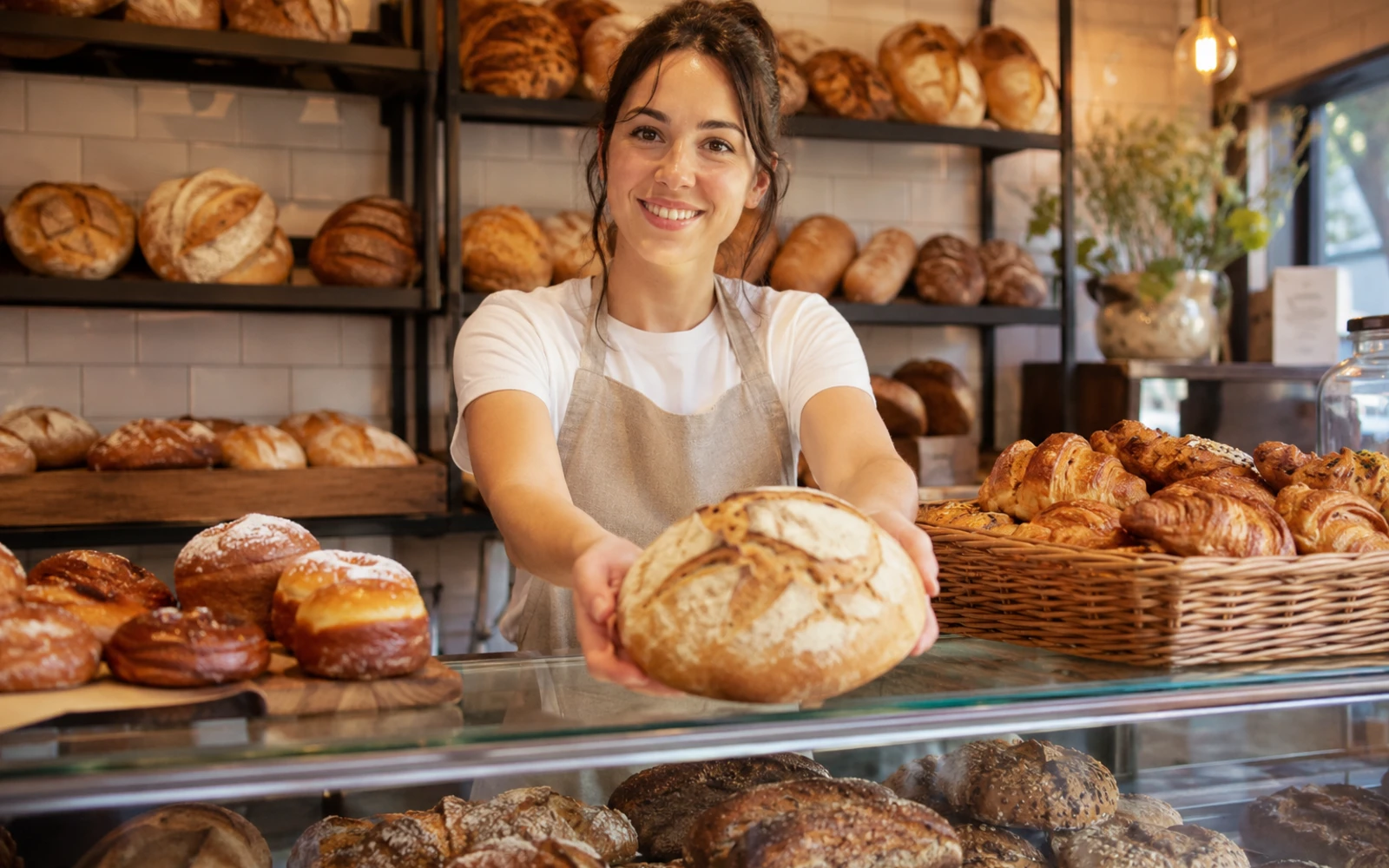 Freundliche Bäckerin hinter dem Tresen mit frischem Brot und Gebäck